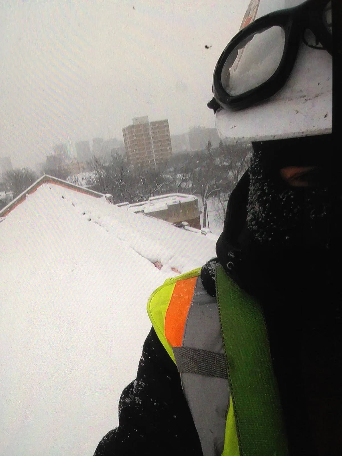 Roofer in full winter PPE looking out over the snow-covered Edmonton skyline