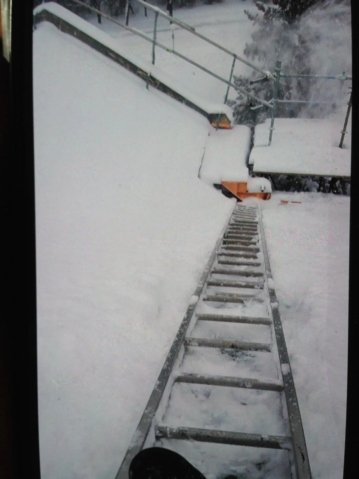 Ladder laid flat up a steep, snow-covered roof slope